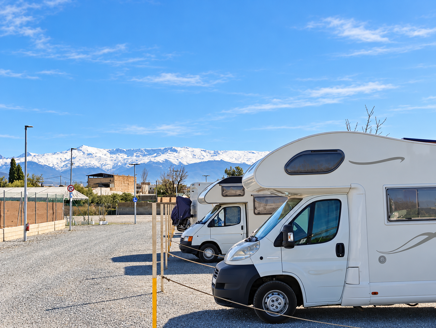 Autocaravanas en Área Camper Bellavista, Maracena, con luz cálida de la tarde.